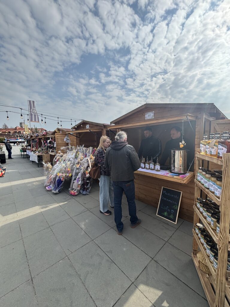 Odwiedzający przy stoisku z miodami na jarmarku wielkanocnym